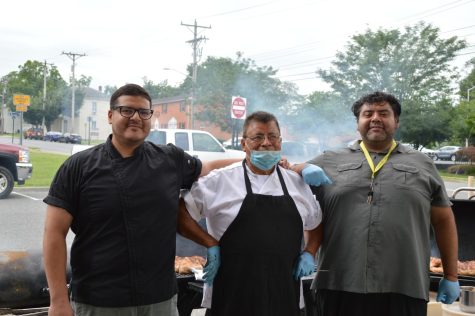 Nelson Garcia, his father, and brother pose for a photo at the Harrisonburg Farmers Market on July 18. Together they cook barbecue chicken to bring light to the original Virginia barbecue. “[My family is involved in this business. I work with my] brother and my father [along with] my other brother and my mother helps out too,” Garcia said. Photo by Eryn Morgan