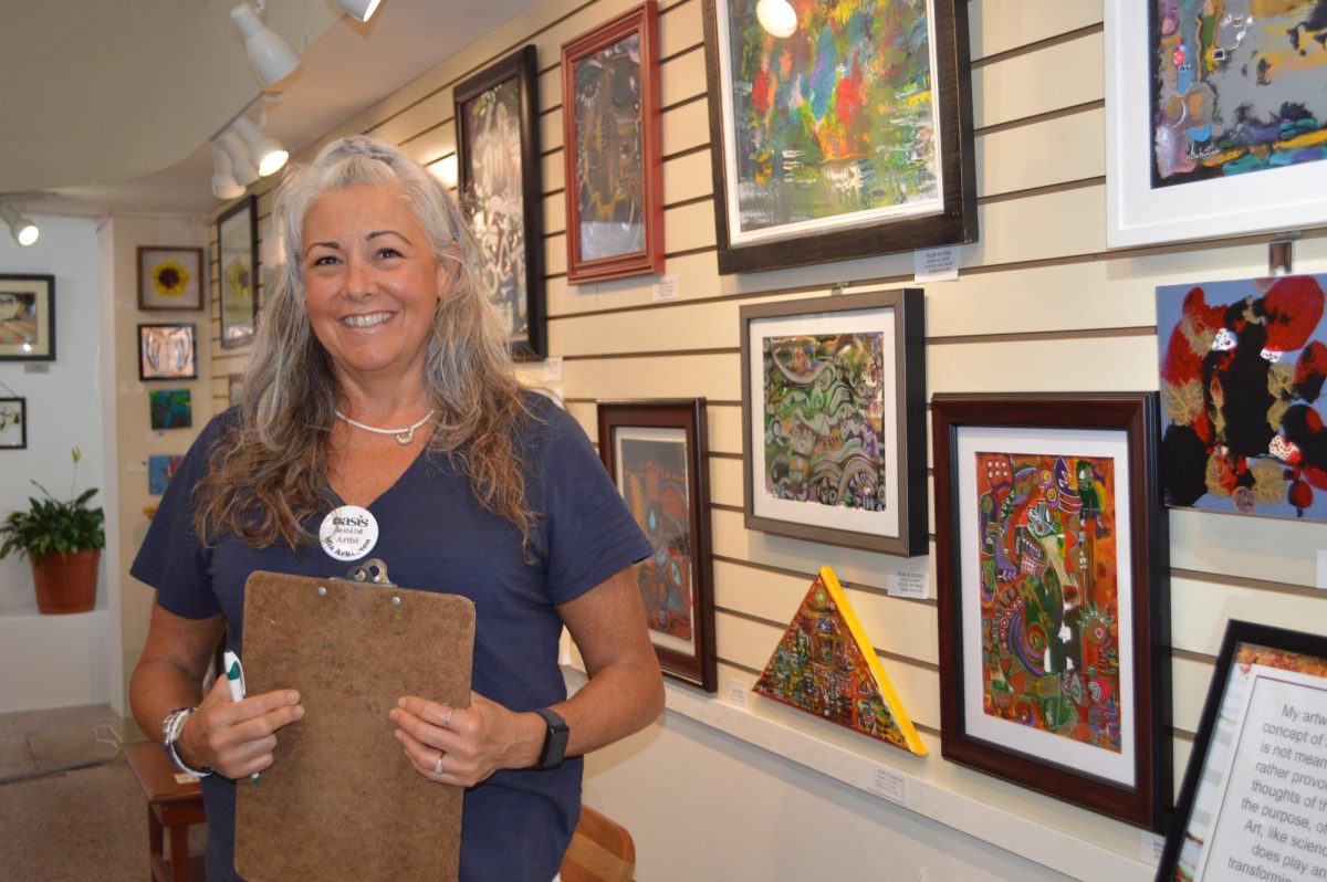 Mia Ackerson, a volunteer at Oasis Fine Arts and Crafts, admires her favorite art pieces by Bahir Al Badry. She enjoys the story behind each of his art pieces. “He talked about his inspiration, and how each one of his pieces mean something,” Ackerson said.