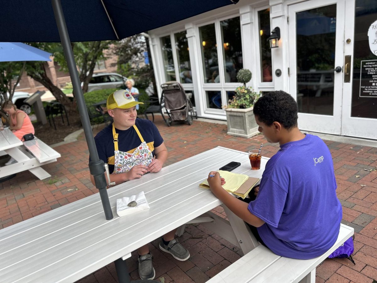 SPILLING THE TEA: Jackson Stamm sits in an interview with Malcolm Washington outside Heritage Bakery & Cafe on South Main Street. Stamm has worked at HBC for a year and enjoys popular music. “Okay, Im really like, Im really into Doja Cat right now. I think that she is like shes making unique music,” Stamm said. 

Photo and caption by Zoe James