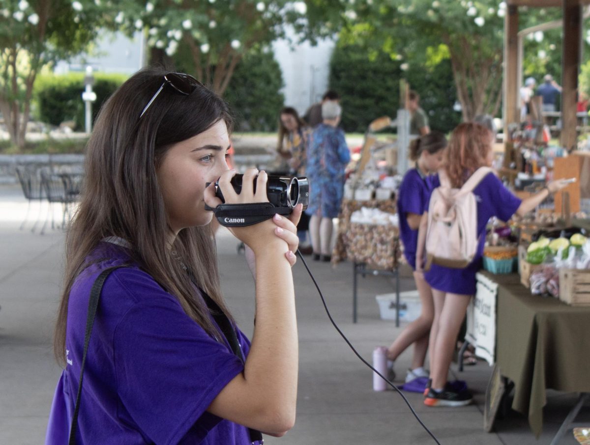 Hayley Gottesman films an interview at the Harrisonburg farmers Market for her story.