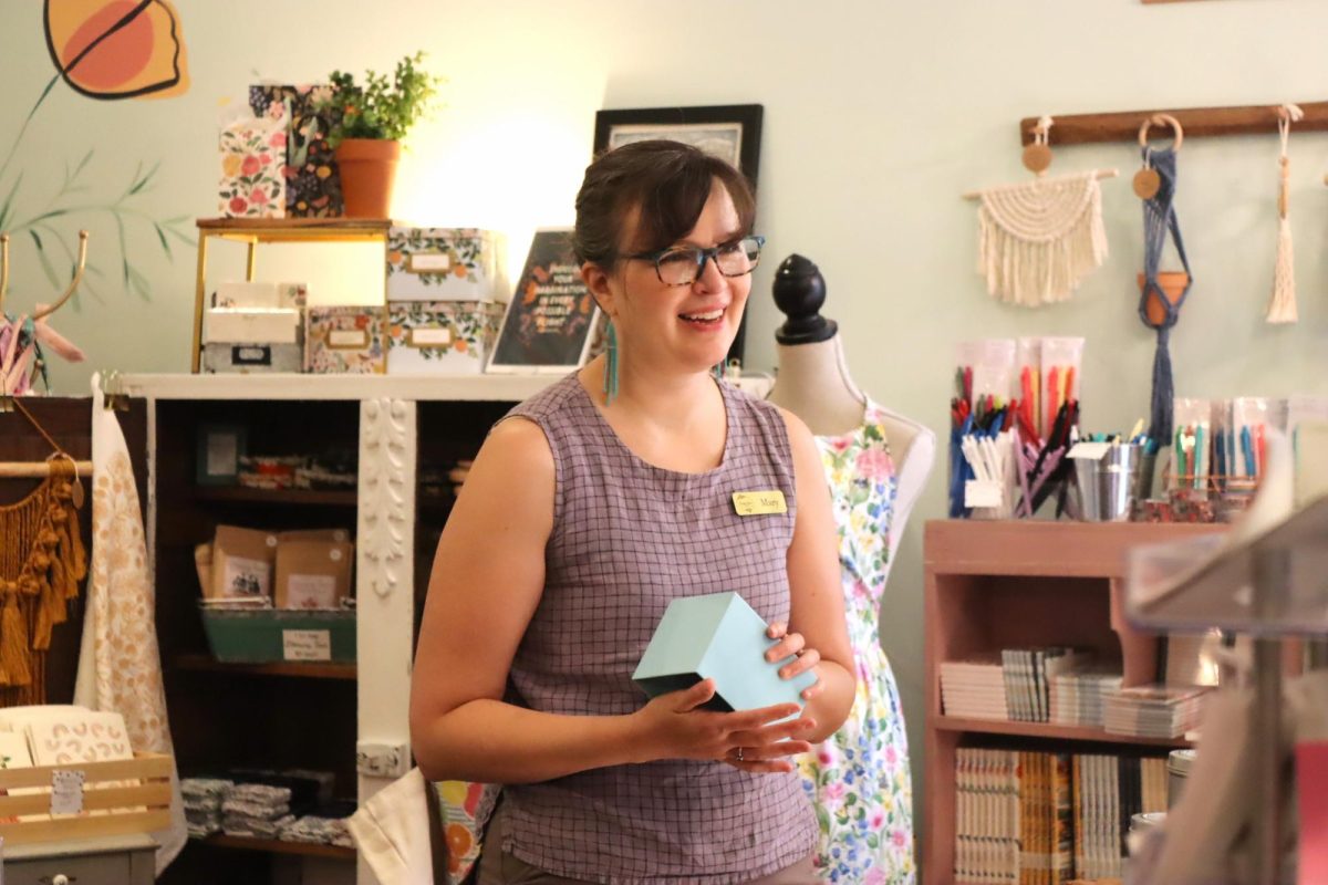 Manager Mary Hairston restocks a product while helping a customer at The Lady Jane. She also makes some of the art that is sold. “I wouldnt wanna work anywhere else,” Hairston said. “I love the creativity and style of products and getting to see the different makers that come through.”