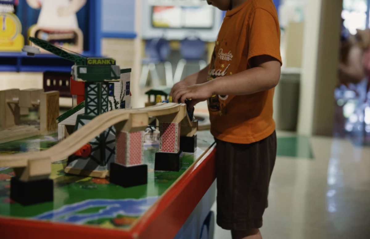 A child plays with a train around in an exhibit. He is having fun playing on trains. The museum is aimed at helping kids develop their motor skills through play.